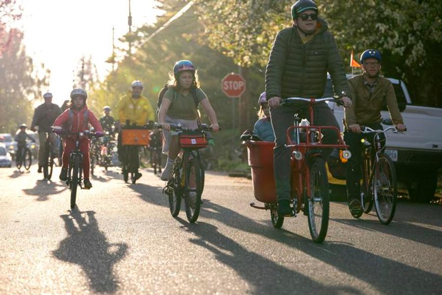 Families riding on the Bike Bus together with the sun behind them