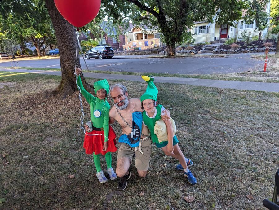 child dressed in a Tingle costume from Legend of Zelda, adult dressed as Daruk from Breath of the Wild, child in a costume as Link from Minish Cap